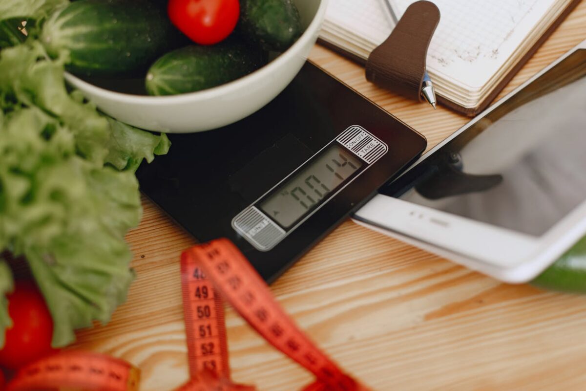 A bowl of fresh vegetables on a kitchen scale with measurement tools, depicting a healthy lifestyle.
