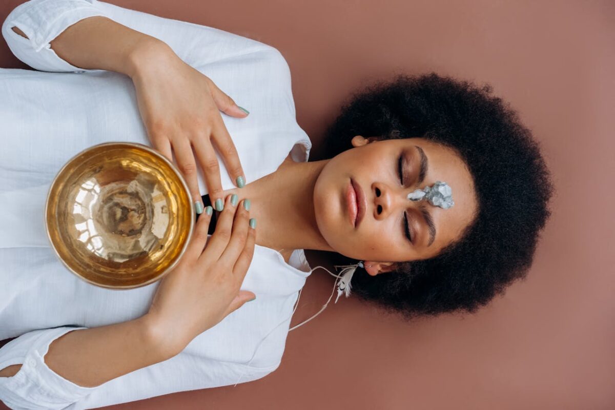 A woman meditates with a Tibetan singing bowl and crystals, promoting wellness and spiritual healing.
